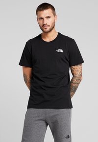 Sort crew neck t-shirt med korte ærmer. Fremstillet af bomuld, med et lille hvidt logo på venstre bryst. Enkel, klassisk design.