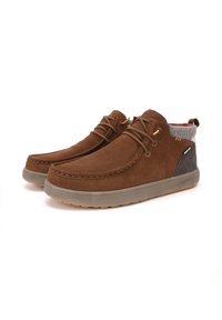 Stivali alla caviglia in suede marrone con suola in gomma, rivestimento in tessuto grigio al colletto e occhielli in tono oro. Punta arrotondata e classica cucitura mocassino.