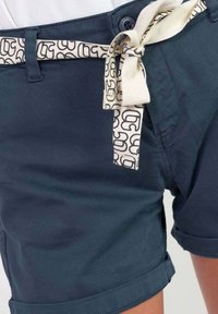 Navyblauwe shorts van een katoenmix met omgeslagen zomen en een lichtbeige riem met patroon en zwarte letters.