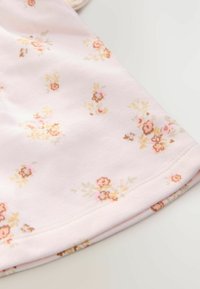 Tissu en coton rose avec une texture douce, présentant un motif floral dans des tons pêche et beige, avec un ourlet arrondi et des coutures soignées.