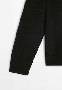 Black knit sweater showcasing a loose-fitting design, ribbed cuffs, and a soft texture. Fabric appears warm and lightweight.