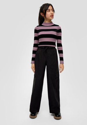 Gestreifter leichter Pullover in Lila und Schwarz mit hohem Kragen, kombiniert mit schwarzen weit geschnittenen Cargo-Hosen mit seitlichen Taschen.