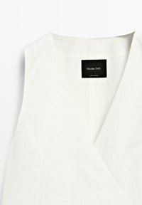 Witte linnen top met een V-hals ontwerp en een label met "Massimo Dutti." De stof heeft een licht gestructureerde afwerking.