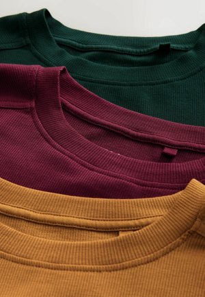 Drei gerippte T-Shirts in einem Stapel: dunkelgrün, bordeauxrot und senfgelb. Jedes hat einen passenden gestrickten Rundhalsausschnitt und eine glatte Textur.