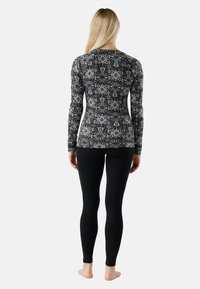Long-sleeve shirt in black and white geometric pattern, paired with black leggings. Form-fitting design with soft, stretchy fabric.