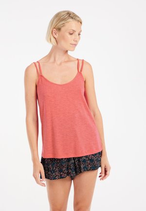 Koraalkleurige tanktop met dunne dubbele bandjes, gecombineerd met zwarte shorts met een bloemenpatroon in roze en blauw. Zachte textuur en een ontspannen pasvorm.