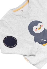 Sudadera gris claro con un lindo pingüino de dibujos animados en el frente y un parche ovalado oscuro en el codo con costura amarilla en la manga.