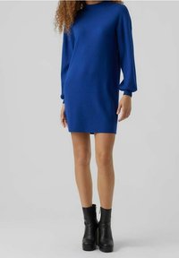 Royalblå stickad klänning med långa ärmar och rundad halsringning. Kombinerad med svarta plattform ankelstövlar. Slät textur, knä-lång snitt.
