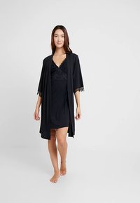 Črna nočna srajca z čipkasto obrobo, skupaj z usklajeno ogrinjalo odprtega sprednjega dela s 3/4 rokavi, oba iz lahkega blaga.