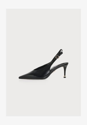 Escarpin slingback en cuir noir à bout pointu, talon fin et bride de cheville ajustable avec boucle ronde dorée sur fond blanc.