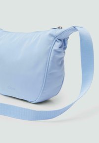 Lichtblauwe schoudertas van soepel nylon, met een gebogen vorm, subtiele plooidetail en een bijpassende geweven schouderband. Zilveren ritsaccent.
