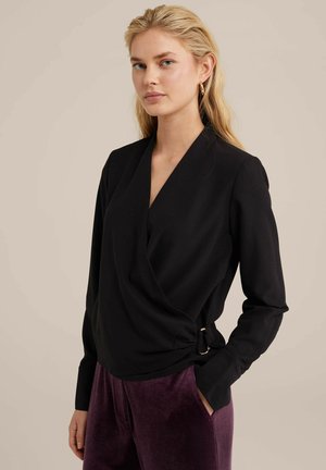 Černý zavinovací top z hladké tkaniny s dlouhým rukávem, výstřihem do V, bočním nařasením a zlatým kováním, spárovaný s fialovými sametovými kalhotami.