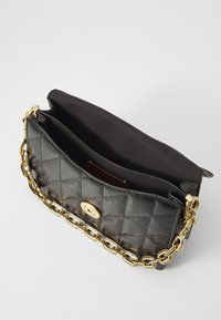 Schwarze, gesteppte Ledertasche mit goldener Kettenriemen, ausgestattet mit einem runden Verschluss, einem glatten Innenraum und ohne sichtbare Außentaschen.