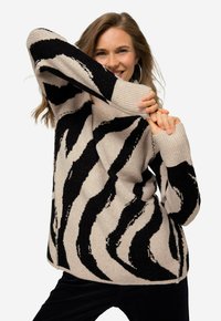 Gestrickter Pullover mit beigem und schwarzem Zebra-Streifenmuster, mit gerippten Bündchen und Saum. Das Material wirkt weich und strukturiert.