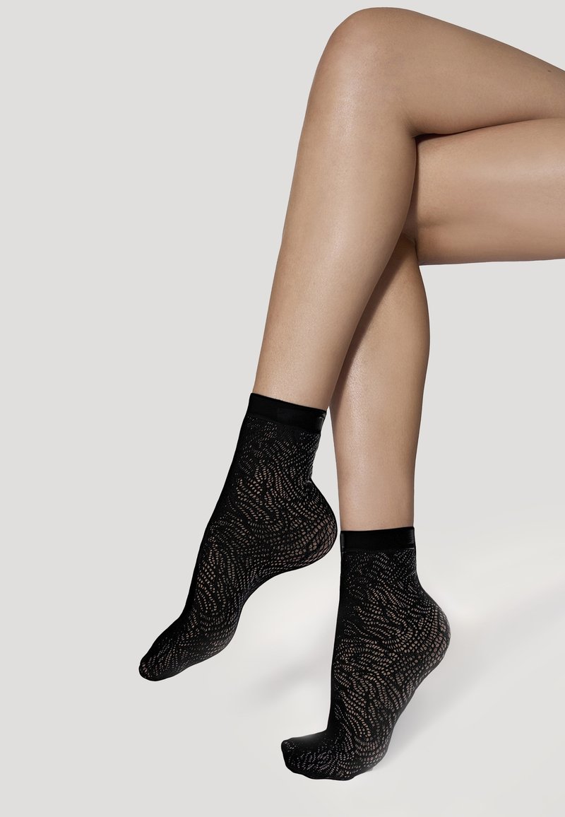Calzini neri alla caviglia con una finitura trasparente e texture che presenta un motivo ondulato. Materiale morbido e bordino elastico per una vestibilità sicura.