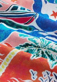 Világos anyag színes hajó, pálmafa, tengeri csillag és óceánhullám mintákkal kék, piros, narancs, zöld és fehér árnyalatokban.