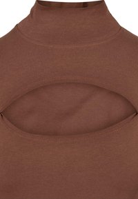 Pruunist venivast kangast mock neck topp, millel on lõikeava disain rinnal, sile tekstuur ja ühtlane õmbluse detail.
