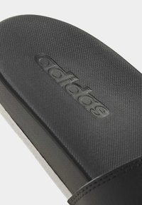 Infradito neri con tomaia texturizzata, logo impresso e suola nera solida con un sottile accento grigio.