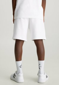 Witte katoenen shorts met een losse pasvorm, aangevuld met witte sokken en casual witte sneakers. Gladde textuur zonder zichtbare patronen.