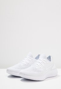 Baskets blanches avec une tige en mesh, bout rond et semelle texturée. Équipées de lacets plats et d'un logo discret sur le côté.