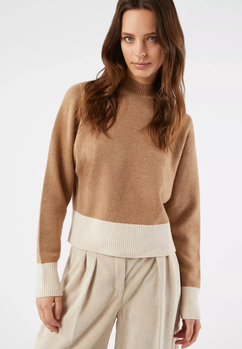 Maglioncino marrone a maglia con collo alto, caratterizzato da un orlo e polsini a coste di colore crema. Texture liscia, vestibilità comoda e design minimalista.