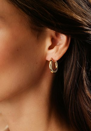 Gold hoop earring with a smooth, polished surface. Features a small latch for closure and a circular, slightly curved design.