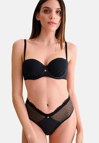 Ensemble de lingerie noire comprenant un soutien-gorge rembourré à motifs en pointillés avec des bordures en dentelle et un slip taille haute assorti avec des panneaux en mesh transparent et des accents en dentelle.