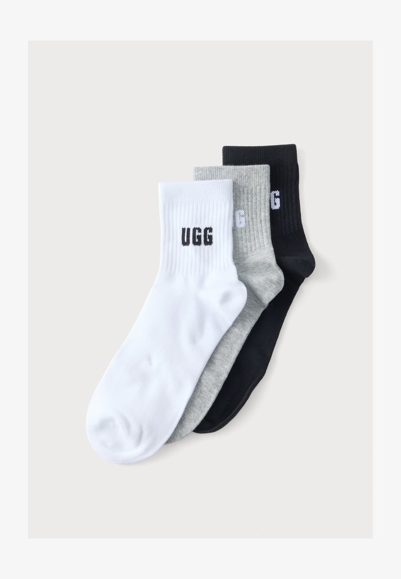 Τρία ζευγάρια κάλτσες UGG σε λευκό, γκρι και μαύρο, στοιβαγμένα και απλωμένα επίπεδα σε ένα απλό ανοιχτό φόντο.