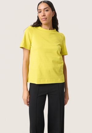 Yellow cotton t-shirt with short sleeves, round neckline, and a relaxed fit, paired with black straight-leg trousers.