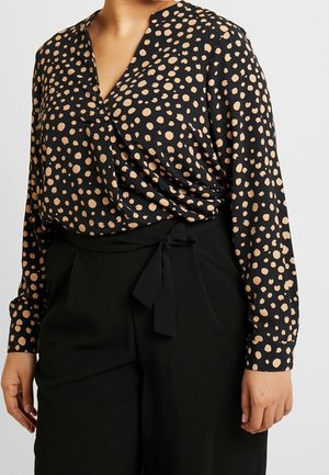 Schwarze Bluse mit goldenen Punkten, V-Ausschnitt, langen Ärmeln und drapierter Gestaltung, kombiniert mit hochtaillierten schwarzen Hosen mit einer Schleifenapplikation.