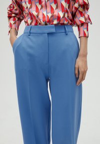 Light blue tailored trousers with a high waist and wide legs, featuring a smooth texture and deep side pockets.