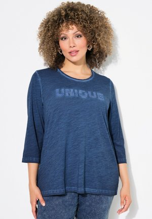 Blauwe, lange mouwen shirt gemaakt van een zachte, gestructureerde stof. Heeft 'UNIQUE' lettering in een lichtere tint aan de voorkant. Ontspannen pasvorm.