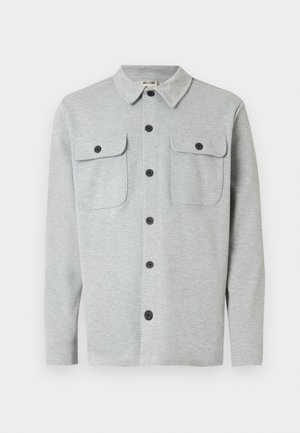Chemise gris clair à manches longues avec boutons, deux poches poitrine à boutons et un col classique, affichée sur un fond blanc.