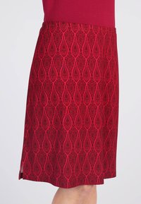 Rote Rock mit einem detaillierten Tropfenmuster und schwarzen Akzenten, seitlichem Schlitz und einer glatten Textur, entworfen für eine figurbetonte Silhouette.