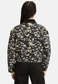 Giacca bomber nera con motivo floreale e design cropped. Presenta un colletto a coste e dettagli con bottoni sul retro.