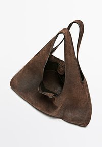 Brązowa zamszowa torba typu tote o trójkątnym kształcie, wyposażona w jedno magnetyczne zapięcie na zatrzask oraz dwa zaokrąglone paski na ramię.