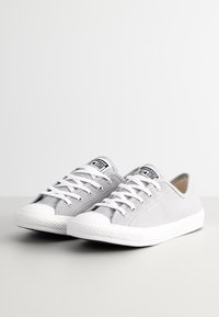 Szare płócienne trampki z białą gumową podeszwą, okrągłym noskiem i białymi sznurówkami. Posiadają czarno-biały emblemat na języku.