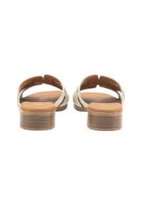 Tacones de sandalia beige con puntera redondeada, diseño abierto y tacón de madera contorneado. Textura suave con una plantilla marrón sutil.