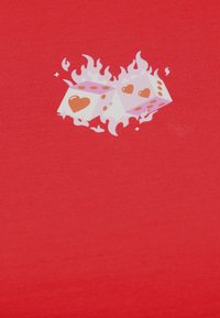 Δύο λευκοί κύβοι με κόκκινη καρδιά και κουκκίδες περιβαλλόμενοι από στυλιζαρισμένες λευκές φλόγες σε κόκκινο υφασμάτινο φόντο.