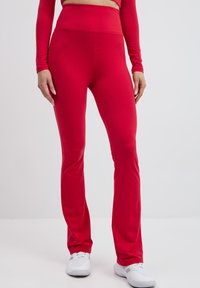 Czerwone legginsy fitness z wysokim stanem, wykonane z gładkiego, elastycznego materiału, z szerokimi nogawkami i minimalnymi dodatkami.