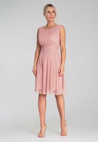 Różowa sukienka w odcieniu blush, bez rękawów, z marszczoną górą i zwiewnym dołem. Wykonana z miękkiego materiału z delikatną nałożoną warstwą. Podkreślona subtelną teksturą.