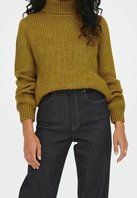 Strickrollkragenspullover in Senfgelb, strukturiertes Material, kombiniert mit hochgeschnittenen dunkelblauen Jeans aus Denim mit Kontrastnähten.