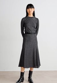 Black ribbed long-sleeve dress with a flared skirt, featuring a fitted waist and subtle texture, paired with shiny black ankle boots.