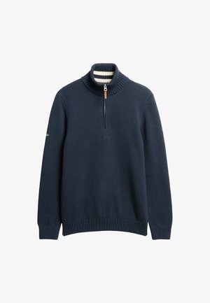 Suéter de punto azul marino con un alto cuello acanalado, media cremallera y puños acanalados. El interior del cuello presenta un patrón a rayas.