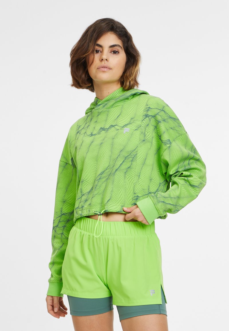 Sudadera recortada en verde brillante con un patrón texturizado, combinada con pantalones cortos a juego. El conjunto incluye un cordón y acentos deportivos.