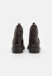 Bottines en cuir marron avec une finition lisse, des panneaux élastiques sur les côtés et un petit talon empilé. Comprend des poignées à l'arrière.