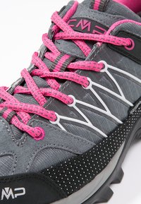 Gray athletic shoe with pink laces, featuring a textured upper, black and white accents, and a patterned sole for grip.