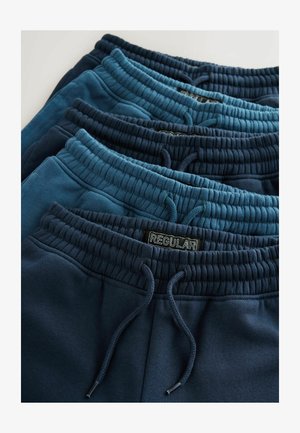 Donkerblauwe joggingbroeken opgestapeld; elastische taillebanden met trekkoorden; het materiaal is zacht met een gladde textuur; het label zegt "REGULIER."