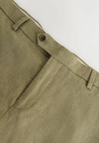 Olivovo zelené nohavice z textúrovaného materiálu. Majú zapínanie na gombík, pútka na opasok a rovný predný strih.