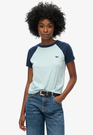 Lichtblauw T-shirt met marineblauwe raglanmouwen, met een klein logo op de borst. Gecombineerd met hoogwaisted blauwe spijkerbroek en een zwarte riem.